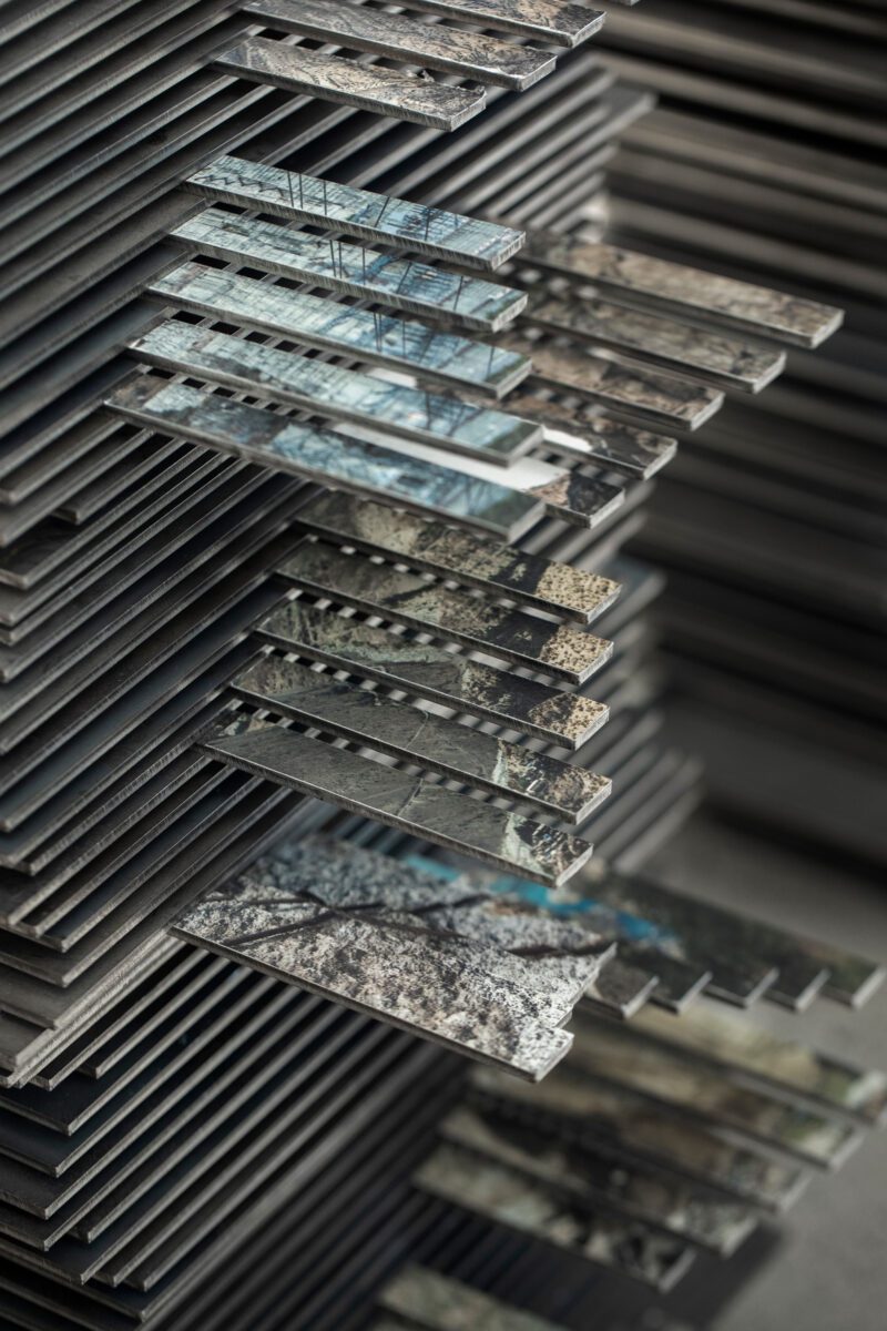 a photobok sculpture by gareth phillips, made using 553 stacked layers of 3mm steel, 2500 3mm magnets and 90 images cut and stacked to mimic staircases accending and decending the steel chapter stacks