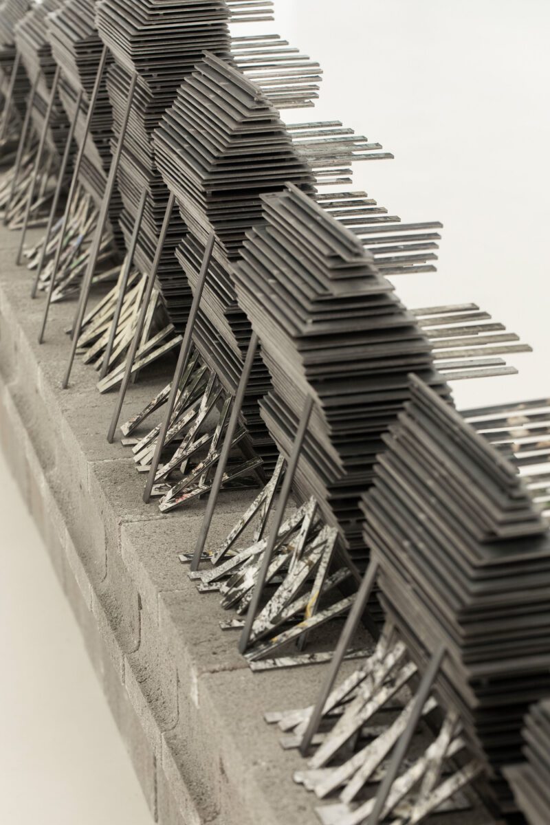 a photobok sculpture by gareth phillips, made using 553 stacked layers of 3mm steel, 2500 3mm magnets and 90 images cut and stacked to mimic staircases accending and decending the steel chapter stacks